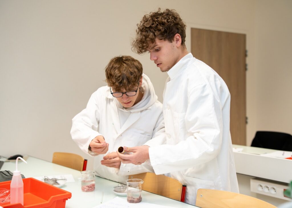 Deux eleves en blouse blanche pendant un travail pratique de sciences