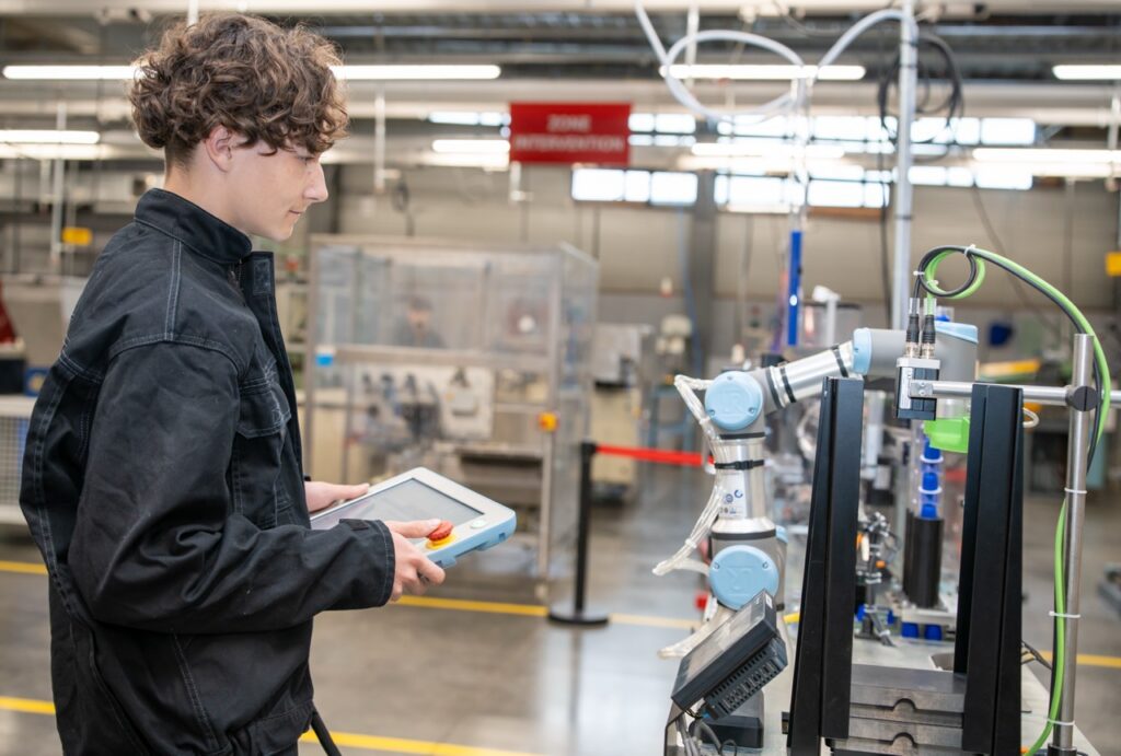 Etudiant en BTS pilotant un bras robotise avec une tablette